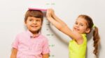 boy and girl measure height by wall scale at home