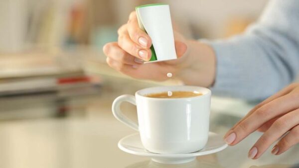 woman hand throwing saccharin pills on coffee cup