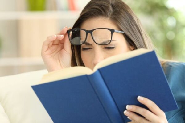 woman suffering eyestrain reading a book